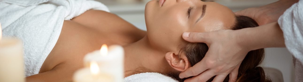 Young beautiful brunette girl having face massage relaxing in spa salon. Eyes closed. Copy space.